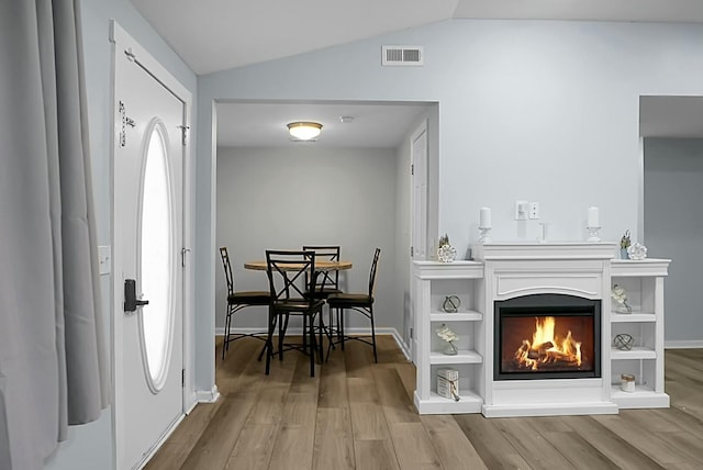 entryway featuring light wood-type flooring, a wealth of natural light, and lofted ceiling