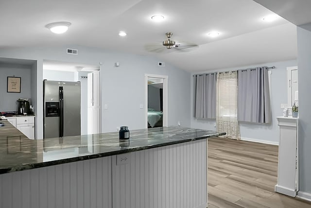 kitchen featuring white cabinetry, stainless steel refrigerator with ice dispenser, light hardwood / wood-style flooring, kitchen peninsula, and lofted ceiling