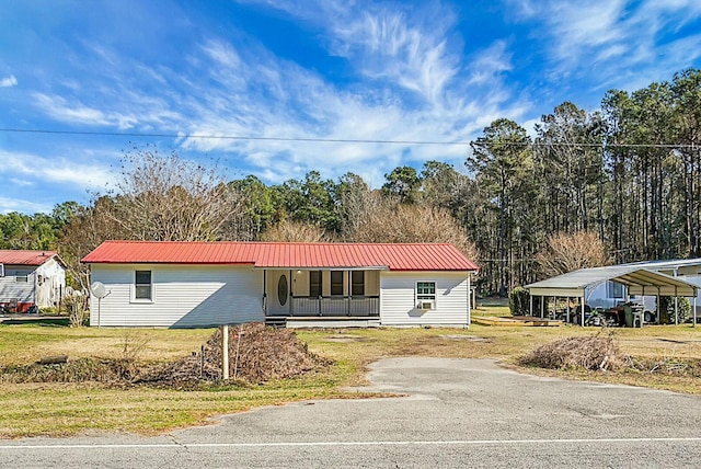 view of front of house with covered porch, a front yard, and a carport