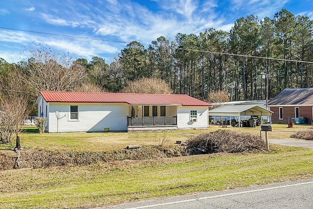 view of front of home featuring covered porch, a front yard, and a carport