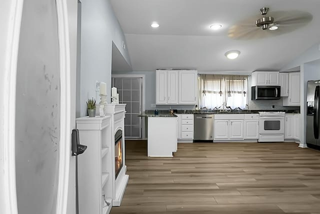 kitchen featuring white cabinetry, decorative backsplash, light wood-type flooring, stainless steel appliances, and lofted ceiling