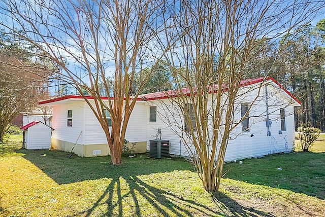 exterior space with central AC unit, a lawn, and a storage unit