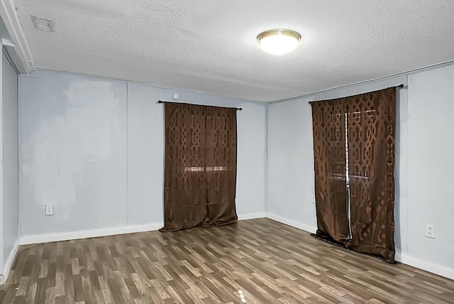 unfurnished room with dark hardwood / wood-style flooring and a textured ceiling