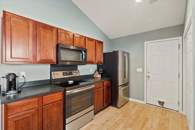 kitchen featuring stainless steel appliances, vaulted ceiling, and light wood-type flooring