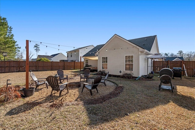 rear view of property featuring a yard and an outdoor fire pit