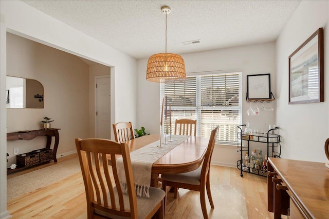 dining room with a textured ceiling and light wood-type flooring