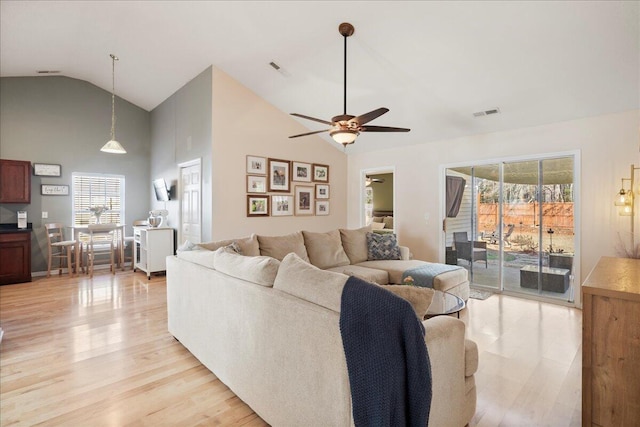 living room with ceiling fan, high vaulted ceiling, a healthy amount of sunlight, and light wood-type flooring