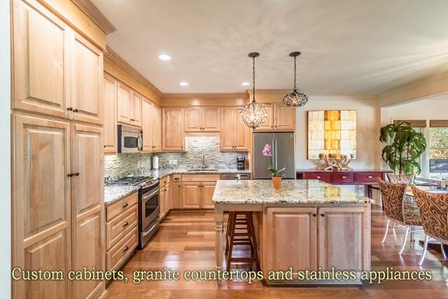 kitchen featuring stainless steel appliances, a kitchen island, sink, and light stone counters