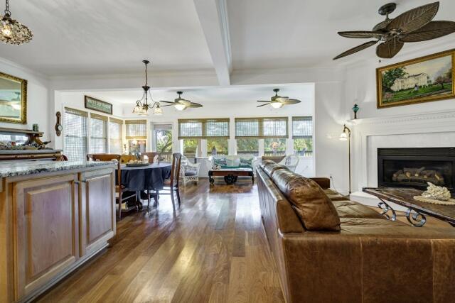 living room with beam ceiling, a healthy amount of sunlight, dark wood-type flooring, and a chandelier