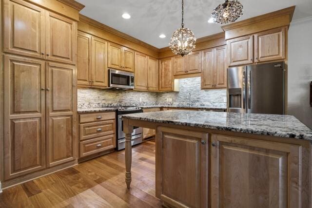 kitchen featuring decorative light fixtures, stainless steel appliances, a center island, and stone countertops