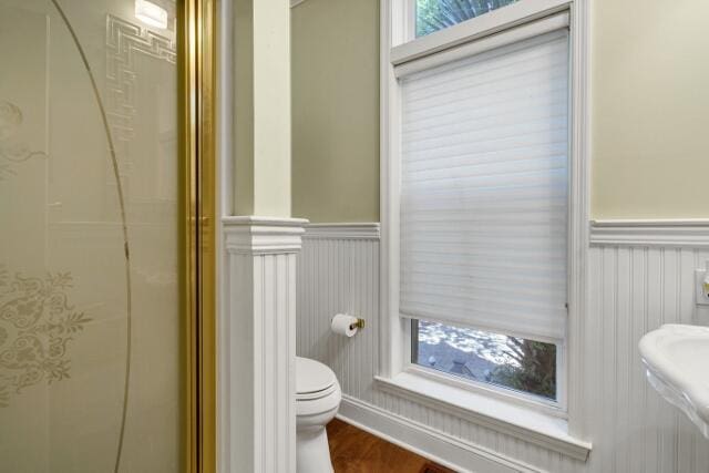 bathroom with hardwood / wood-style floors, a shower with door, and toilet