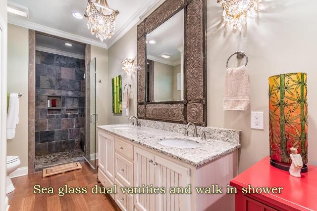 bathroom with hardwood / wood-style floors, vanity, a notable chandelier, ornamental molding, and toilet