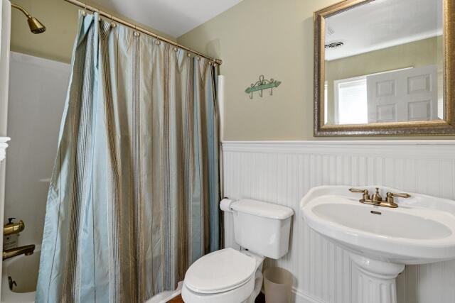 full bathroom featuring sink, shower / tub combo with curtain, and toilet