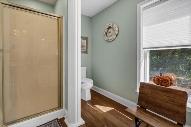 bathroom with hardwood / wood-style flooring, toilet, and an enclosed shower