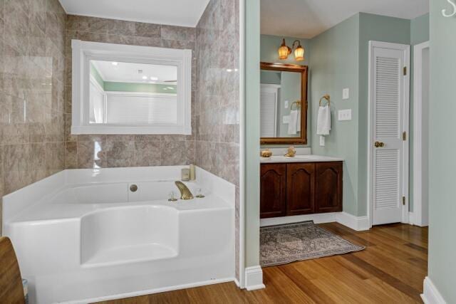 bathroom with hardwood / wood-style flooring, vanity, a bathing tub, and tile walls