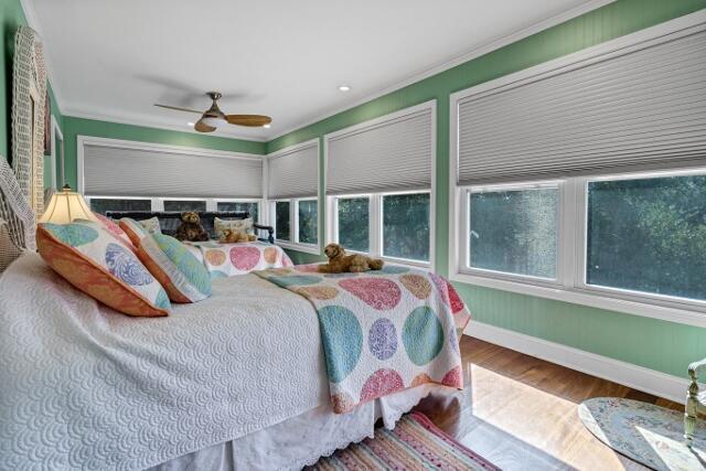 bedroom with wood-type flooring, ornamental molding, and ceiling fan