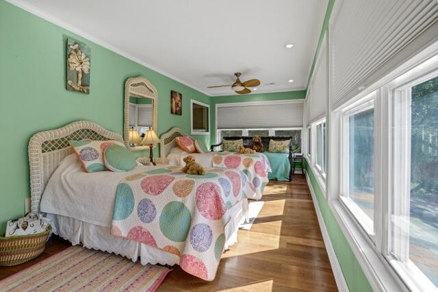 bedroom featuring dark wood-type flooring, ceiling fan, crown molding, and multiple windows