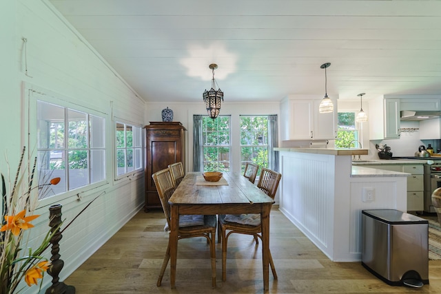 dining area with light wood-type flooring, sink, and a chandelier