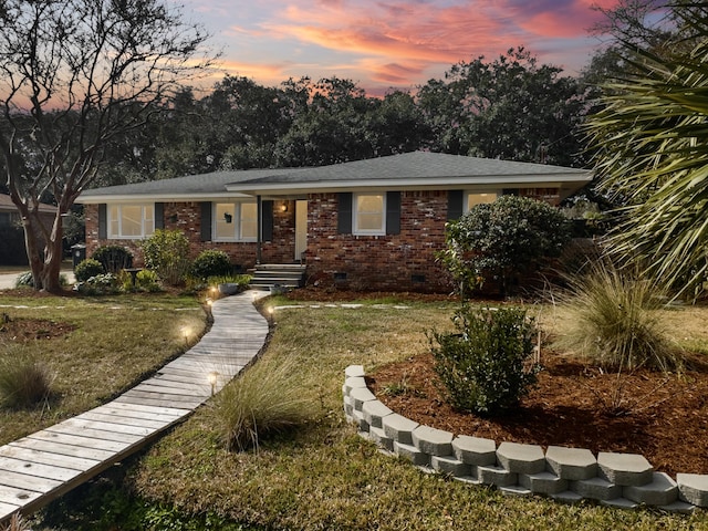 ranch-style house with crawl space, brick siding, and a lawn