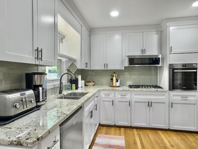 kitchen featuring white cabinets, light wood finished floors, stainless steel appliances, and a sink