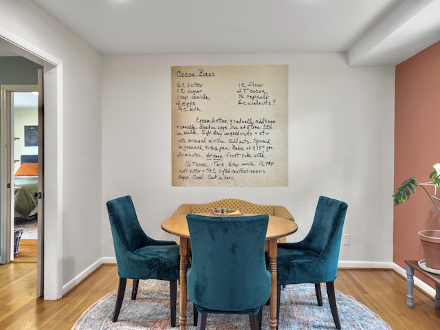 dining area with baseboards and wood finished floors