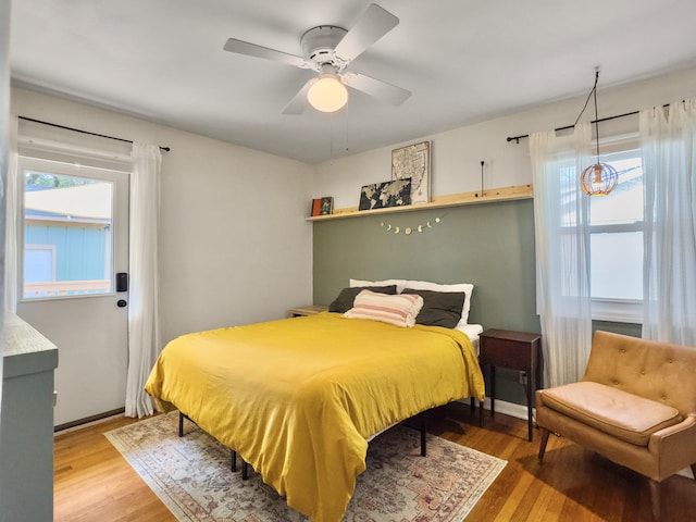 bedroom featuring ceiling fan, multiple windows, and wood finished floors