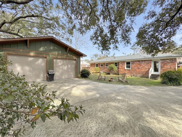 view of home's exterior featuring brick siding, a detached garage, board and batten siding, entry steps, and fence