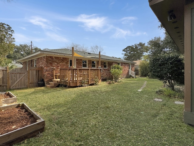 view of yard featuring a vegetable garden, a gate, fence, and a wooden deck