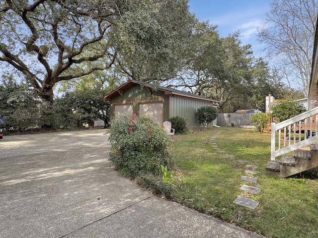 view of side of home featuring an outbuilding, a lawn, fence, and a garage