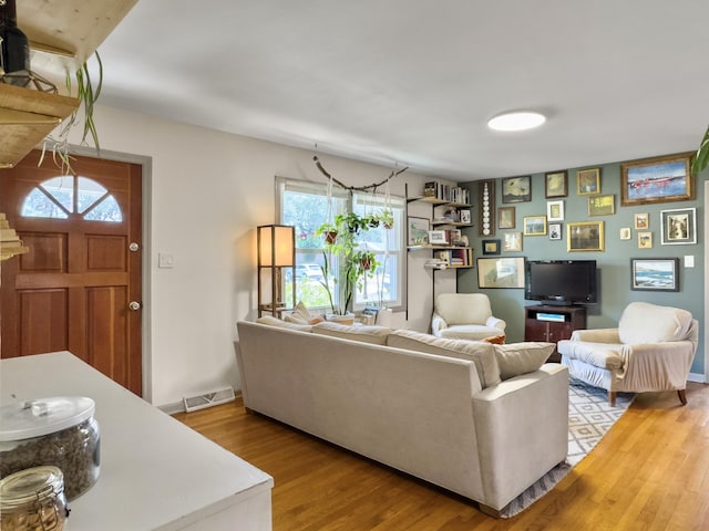 living room featuring light wood finished floors, visible vents, and baseboards