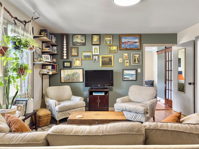 living room with a barn door and wood finished floors