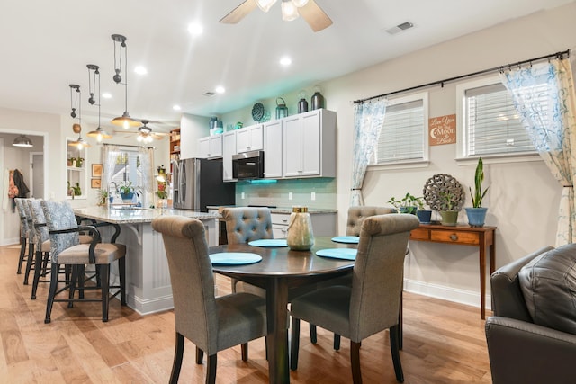 dining space with ceiling fan and light hardwood / wood-style flooring