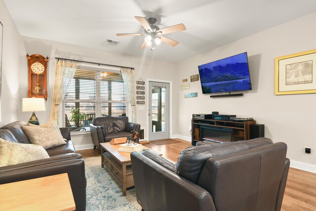 living room with ceiling fan, a fireplace, and hardwood / wood-style floors