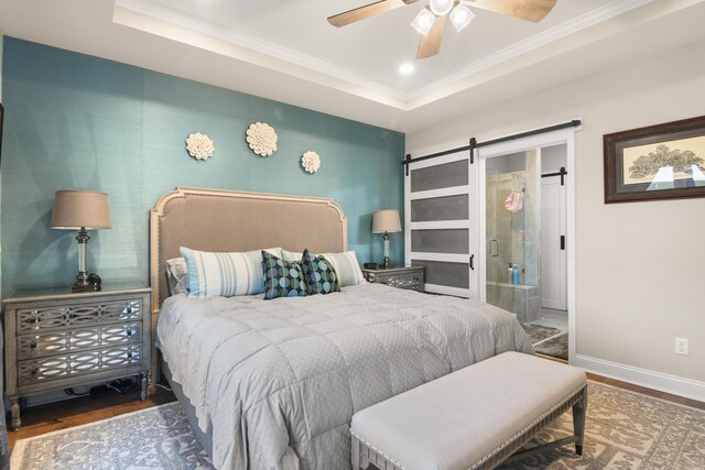 bedroom featuring crown molding, ceiling fan, wood-type flooring, a raised ceiling, and a barn door