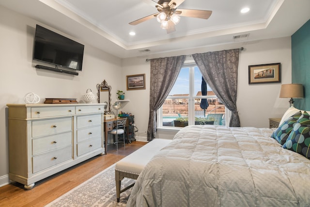 bedroom featuring crown molding, hardwood / wood-style floors, a tray ceiling, and ceiling fan