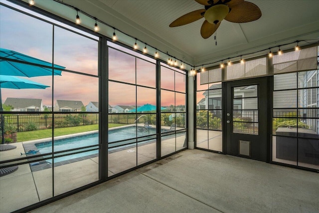 unfurnished sunroom with rail lighting and ceiling fan