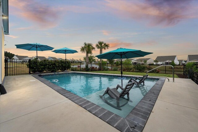 pool at dusk with a patio area