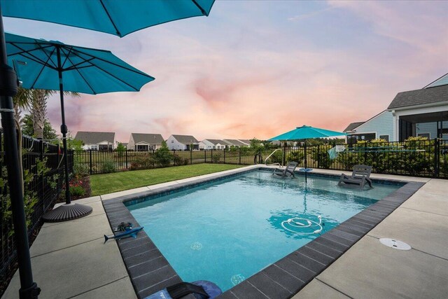 pool at dusk with a yard and a patio area