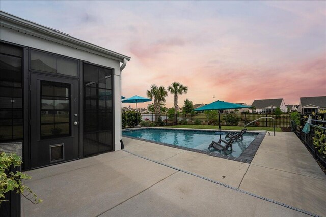 pool at dusk with a patio area