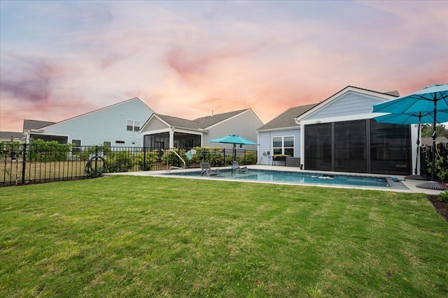 pool at dusk featuring a sunroom and a lawn