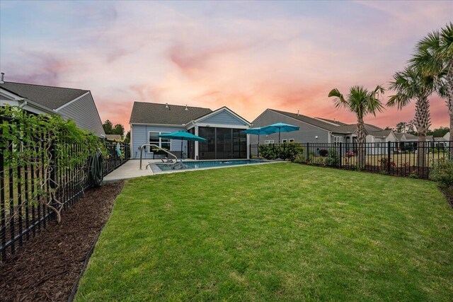 yard at dusk featuring a fenced in pool, a sunroom, and a patio area