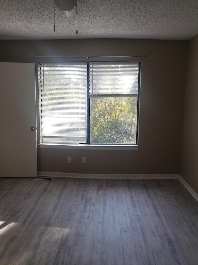 spare room featuring hardwood / wood-style floors and a textured ceiling