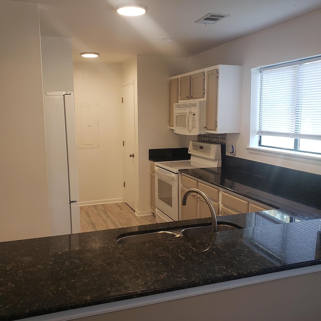 kitchen featuring light hardwood / wood-style floors, white appliances, sink, and dark stone counters