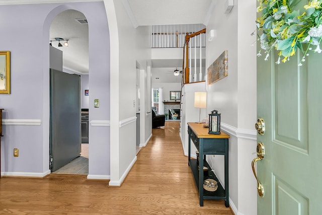 3257 Heathland Way, Mount Pleasant, SC 29466 - entrance foyer featuring a ceiling fan, light wood-style floors, a warm lit fireplace, and arched walkways