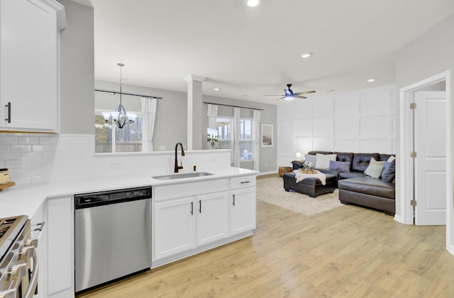 kitchen featuring sink, stainless steel dishwasher, white cabinets, pendant lighting, and stove