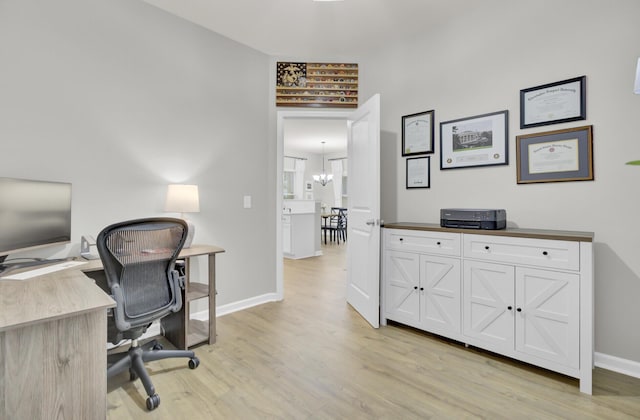 home office with a notable chandelier and light wood-type flooring