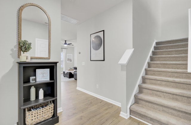 stairs featuring wood-type flooring and ceiling fan