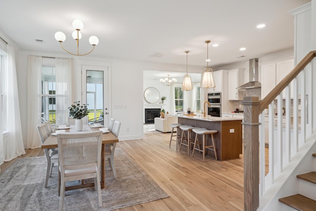 dining space featuring light wood finished floors, visible vents, stairs, and an inviting chandelier