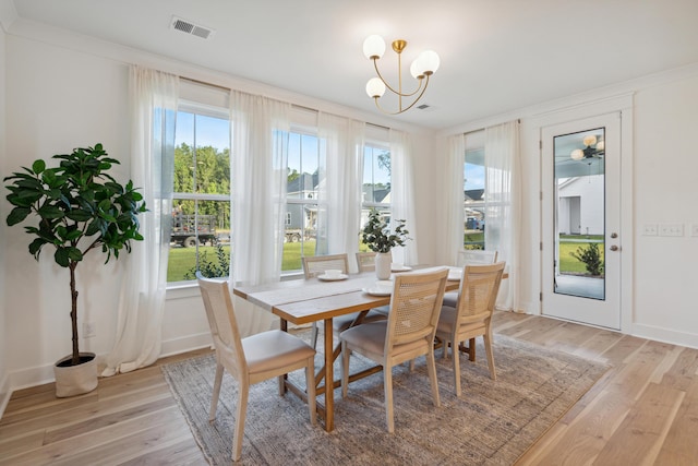 dining area featuring visible vents, light wood-style flooring, ornamental molding, baseboards, and a chandelier