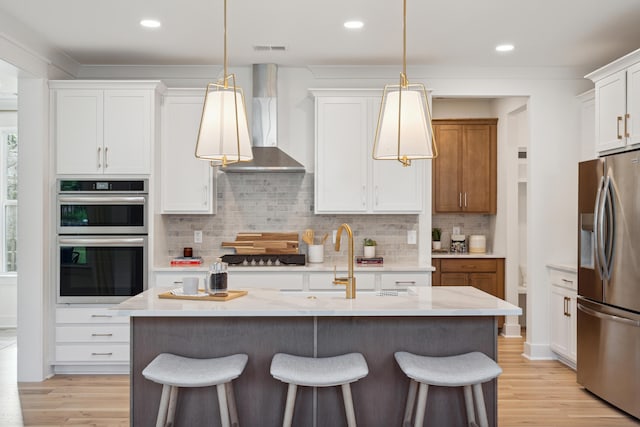 kitchen with a sink, wall chimney range hood, a breakfast bar area, and stainless steel appliances